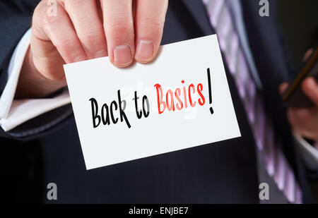 A businessman holding a business card with the words, Back to Basics, written on it. Stock Photo