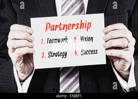 A businessman holding a business card with a Partnership Concept written on it. Stock Photo