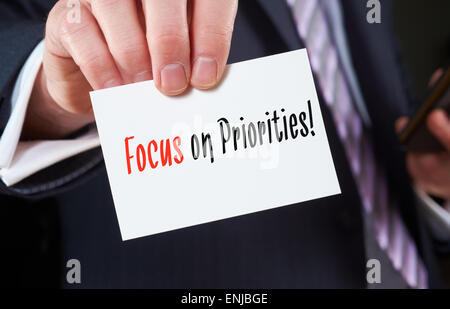 A businessman holding a business card with the words,  Focus on Priorities. Stock Photo