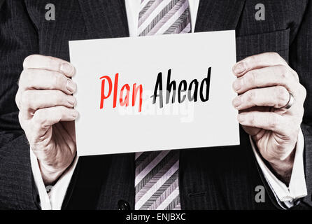 A businessman holding a business card with the words, Plan Ahead, written on it. Stock Photo