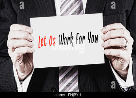 A businessman holding a business card with the words, Let Us Work For You, written on it. Stock Photo