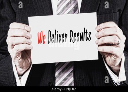 A businessman holding a business card with the words,  We Deliver Results, written on it. Stock Photo