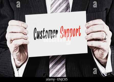 A businessman holding a business card with the words, Customer Support, written on it. Stock Photo