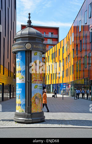 Cylindrical advertising morris column inscribed Barking & Dagenham with colourful modern architecture Barking town centre England UK previously Essex Stock Photo