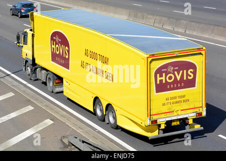 View from above side & back Hovis yellow hgv supply chain bread delivery lorry truck & articulated trailer brand advert driving along m25 motorway UK Stock Photo