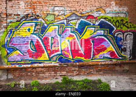 Saint-Petersburg, Russia - May 6, 2015: Abandoned urban courtyard with colorful abstract graffiti text pattern on old brick wall Stock Photo