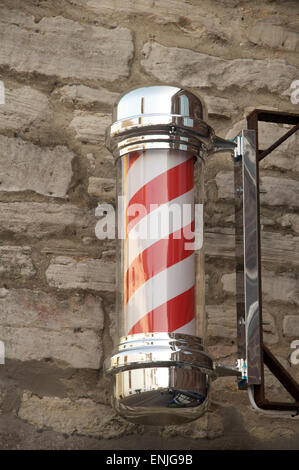 The red and white striped helix of a traditional barbers pole. Fixed to a wall above a gentlemen’s hairdressers shop in England. United Kingdom. Stock Photo