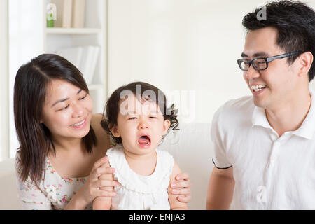 Parents is comforting their crying daughter. Asian family at home. Stock Photo