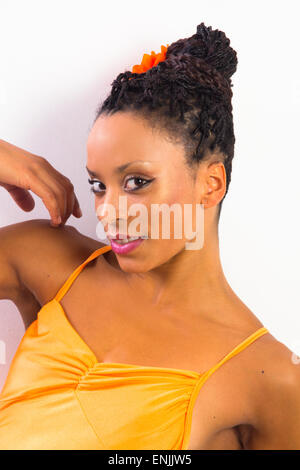 African female ballerina in a modern dance pose wearing orange leotard Stock Photo