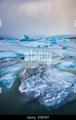 Frozen icebergs locked in the frozen waters of Fjallsarlon Glacier lagoon, South East Iceland, Iceland, Polar Regions Stock Photo