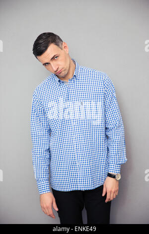 Upset young man standing over gray background and looking at camera Stock Photo