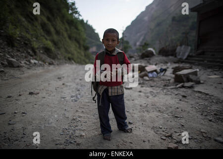 Kobani, Kobani, Nepal. 5th May, 2015. A boy is pictured as he's standing with the destroyed abandoned village behind him, on the Araniko Road near the Kobani Village (Tibetan Border).Isolated Nepalese Villagers still waiting for help and worry about an other earthquake happen.Most of the houses from ''Dolalgat'' to ''Kobani'' (around 65km) collapsed, destroyed by huge stones fell from the mountains, (and stones are still falling as now), around 5 or 6 earthquakes are felt every day and night, and people didn't get any help from anyone, the phone network doesn't work, they got enough food for Stock Photo