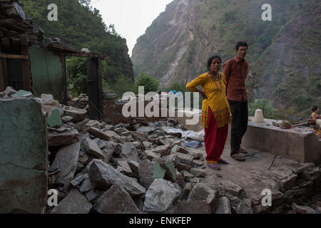 Kobani, Kobani, Nepal. 5th May, 2015. A woman and her son are pictured standing inside their collapsed house on the Araniko Road near the Kobani Village (Tibetan Border).Isolated Nepalese Villagers still waiting for help and worry about an other earthquake happen.Most of the houses from ''Dolalgat'' to ''Kobani'' (around 65km) collapsed, destroyed by huge stones fell from the mountains, (and stones are still falling as now), around 5 or 6 earthquakes are felt every day and night, and people didn't get any help from anyone, the phone network doesn't work, they got enough food for only 2 more Stock Photo