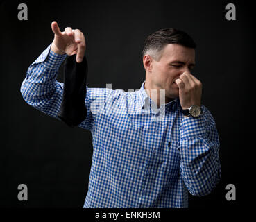 Man holding smelly socks and clogged nose over black background Stock Photo