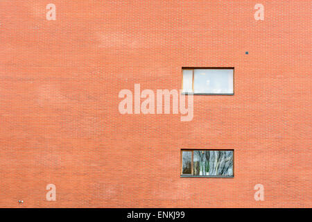 Huge brick wall on modern building with two windows. Reflections in windows. Copy space to the left. Stock Photo