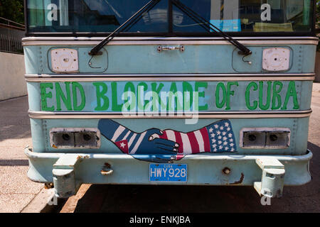 End Blockade of Cuba written on a bus in Cuba with  Cuban and American flag painted on hands and shaking hands Stock Photo