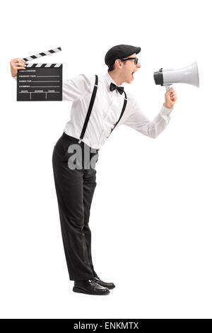 Full length profile shot of a young movie director holding a clapperboard and shouting on a megaphone Stock Photo