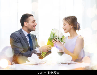 smiling man giving flower bouquet at restaurant Stock Photo