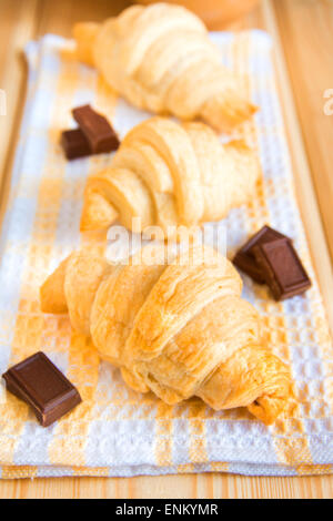 Homemade croissants with chocolate on napkin and wooden table Stock Photo