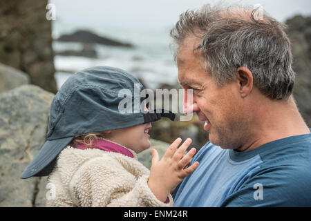 Father plays peek-a-boo with toddler daughter using his baseball cap at Patrick's Point State Park, California. Stock Photo