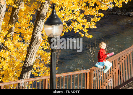 A young girl reading on the Animas River Trail in Durango, Colorado.