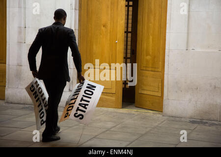 Hackney, London, UK. 07th May, 2015. After a long day of voting across the the country in the general election the polling stations close. A polling station officer at Hackney Town Hall takes down the signage shortly after 10pm. Credit:  Kristian Buus/Alamy Live News Stock Photo