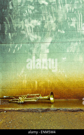 Old worn trumpet stands alone against a grungy wall outside a jazz club Stock Photo