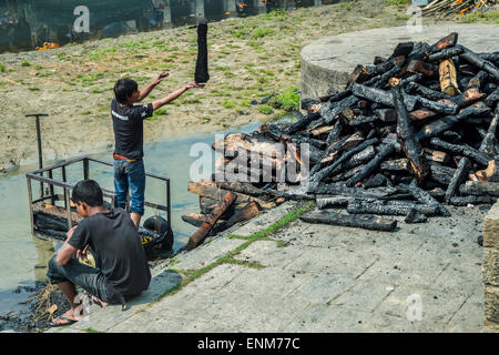 Child labour - Kids sorting burnt logs after a cremation at Pashupatinath temple, in Kathmandu Stock Photo