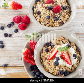 Muesli,  fresh berries and yogurt for  breakfast  on a wooden table. Stock Photo