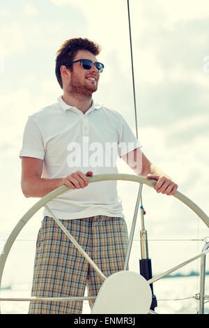 young man in sunglasses steering wheel on yacht Stock Photo