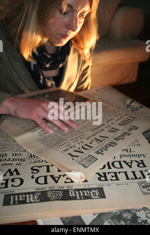 Normandy, France, 8th May 2015. British ex-pat, Julia White, reads an old copy of The Daily Sketch newspaper, Britian's oldest tabloid. The paper announces Victory in Europe Day WWII on Tuesday 8th May 1945. Credit:  Daniel and Flossie White/Alamy Live News Stock Photo