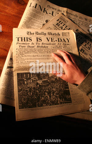 Normandy, France, 8th May 2015. British ex-pat, Julia White, reads an old copy of The Daily Sketch newspaper, Britian's oldest tabloid. The paper announces Victory in Europe Day WWII on Tuesday 8th May 1945. Credit:  Daniel and Flossie White/Alamy Live News Stock Photo