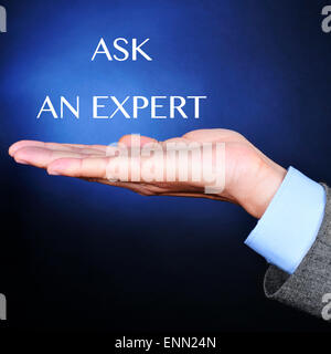 the hand of a young caucasian man wearing a gray suit and the text ask an expert on a black background lightened in blue Stock Photo
