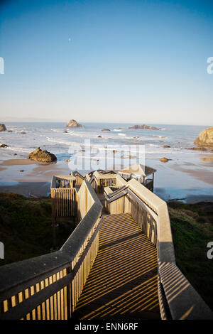 The morning sun shines on a long wooden staircase that leads down to Bandon Bay on the Oregon Coast. Stock Photo