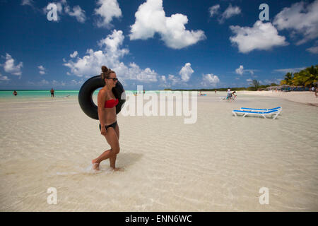 A young woman carries her inflatable tube back to the beach while on vacation in Cayo Coco, Cuba. Stock Photo