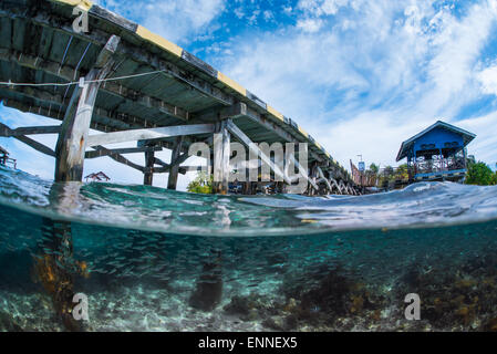 A split shot of both the surface and the underwater scenery at aerbork vilage jetty in Raja Ampat Stock Photo