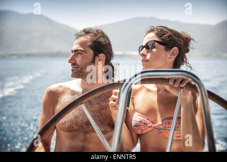 Beautiful couple on sailboat, young happy family behind helm of luxury water transport, having fun in the sea Stock Photo