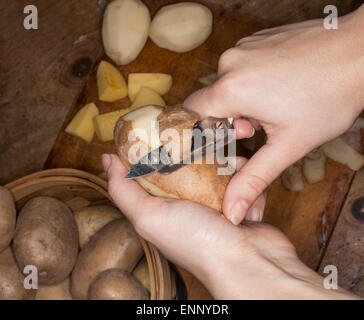 Woman peeling and cutting raw patatoes in the kitchen. Stock Photo