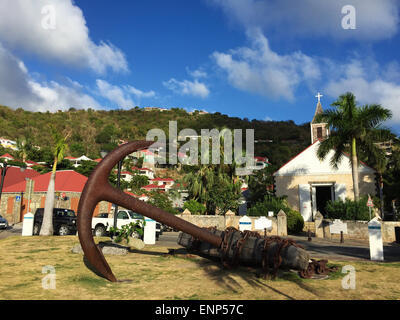 Saint-Barthélemy, French West Indies, Caribbean: a sculpture in the form of an anchor, the skyline of Gustavia and the Anglican Church Stock Photo