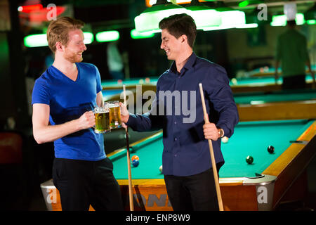 Young men playing pool and drinking beer Stock Photo