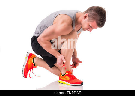 Handsome young man kneeling and tying sneaker, ready to run. Isolated on white Stock Photo