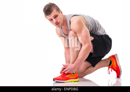 Handsome young man kneeling and tying sneaker, ready to run. Isolated on white Stock Photo