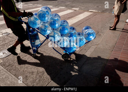 A delivery person wheels a cart of bottled water across a San Francisco street. Stock Photo