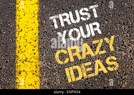 TRUST YOUR CRAZY IDEAS motivational quote. Yellow paint line on the road against asphalt background. Concept image Stock Photo