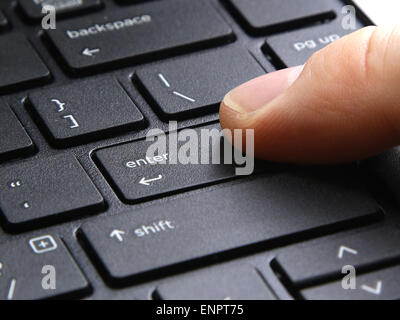 computer enter key with finger pressing button on white background Stock Photo