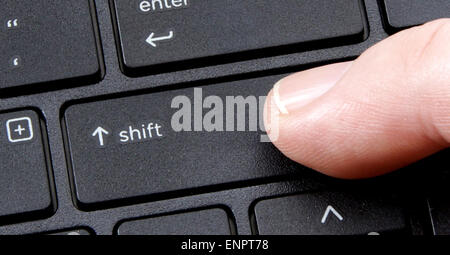 computer shift key with finger pressing button on white background Stock Photo