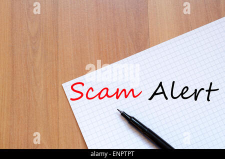 White blank notepad on office wooden table Scam Alert concept Stock Photo