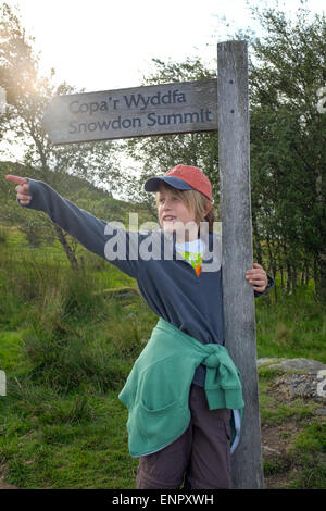 A boy prepares to climb up Mount Snowdon Snowdonia standing next to the path sign Stock Photo