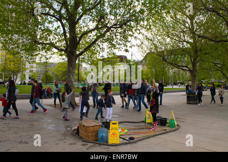 Tourists in Embankment Gardens, London, United Kingdom. Soap Bubble Artist entertaining children. Stock Photo
