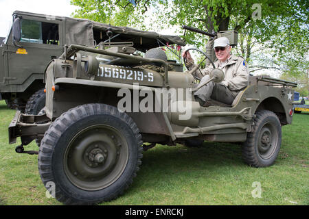 London, UK. 10th May, 2015. The day after the Allies commemerated VE Day, Charles SIlverlight sits behind the wheel of his 1944 Willis Jeep In Bushy Park, London during the Chestnut Sunday celebrations. In World War II Bushy Park was commandeered as the Supreme Headquarters of the Allied Expeditionary Forces and was the base from which General Eisenhower planned the D-Day landings. Chestnut Sunday is the biggest day in the park’s calendar. Stock Photo